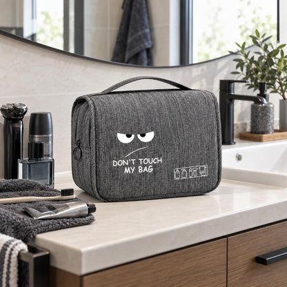 Trousse de toilette grise petit format avec motif humoristique mise en scène sur un meuble de lavabo
