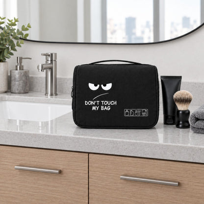 Trousse de toilette homme noire avec motif humoristique mise en scène sur un meuble de lavabo